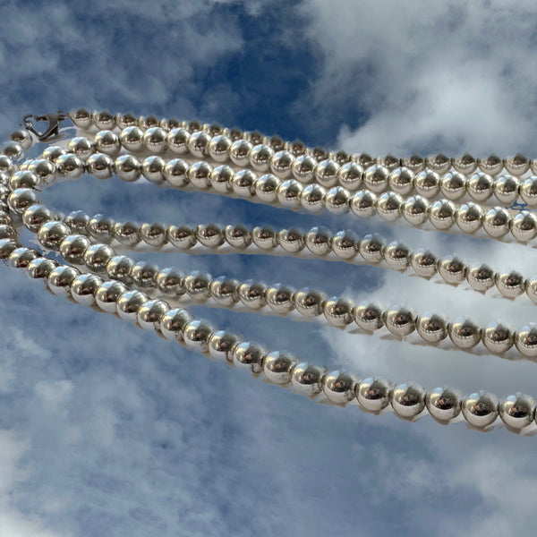 There is a reason these "pearls" are a Fables "Classic". Whether you like Jackie Kennedy or Prince, you should own this extra-long Sterling Silver Pearl necklace with its heart clasp. If you can only take one accessory on any trip, let it be this versatile strand of Silver Pearls.(It is also a perfect gift for a bride!) A generous 5 feet of 7mm Sterling Silver Pearls with a heart clasp. Hand made in the USA. Hand Signed.