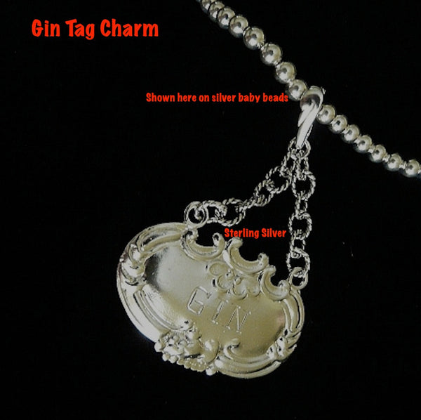 Fablesintheair.com Sterling Silver Gin Tag Ornament Charm.Meant to adorn a neck of a different kind, this Gin Tag adapts beautifully, and why NOT? With its beautiful 2" of on of my most favorite chains attached to the perfect bail, which opens and snaps over beads or pearls easily or slips through the most rugged chain. Engraved and ornate and available in either shiny or my vintage oxidized finish. Even teetotalers like this!  (Chains sold separately.)  1-3/4" x 1" x 2" approximately.  Sterling Silver Gin 